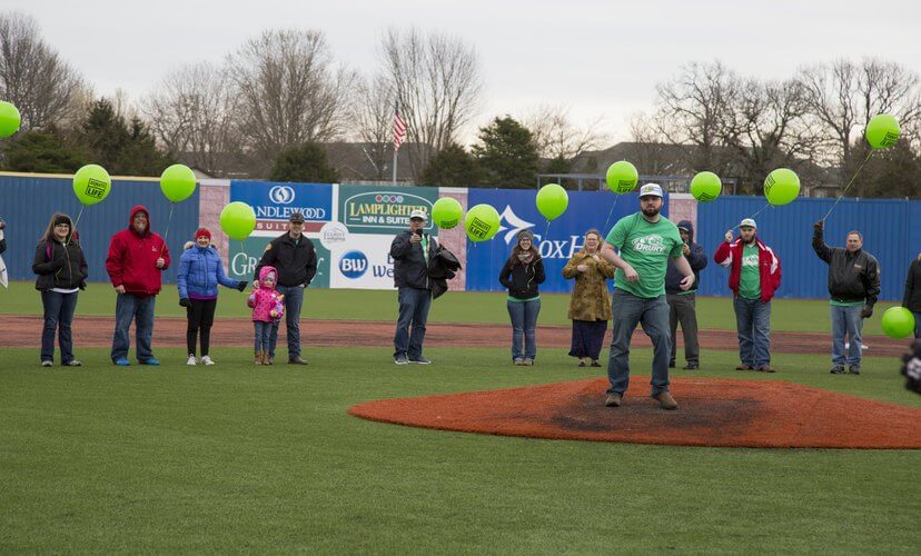 People on baseball field holding balloons
