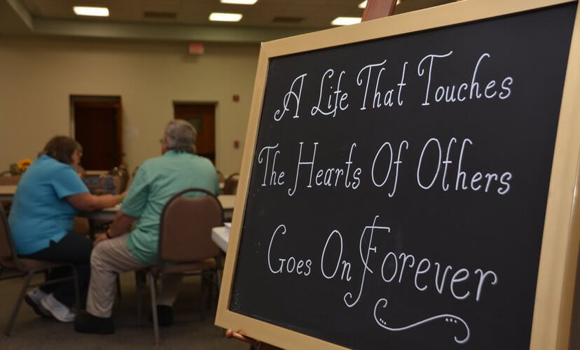 Chalkboard reads "A Life That Touches the Hearts of Others Goes On Forever"