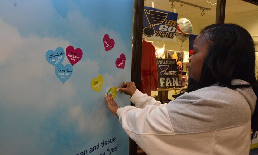 Elvira McGee pins heart with her name on it to the wall.