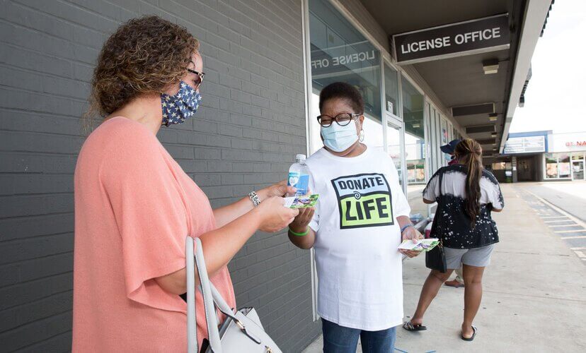 A Mid-America Transplant volunteer hands out water and information about organ and tissue donation at the Florissant DMV.