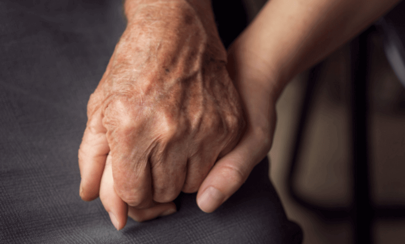 An elderly hand holds a young hand