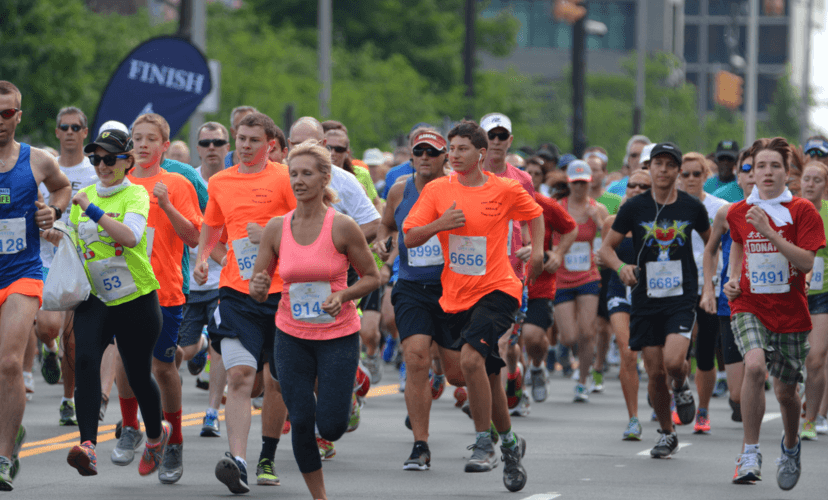 Runners in neon-colored shirts cross the finish line at the 2016 Games in Ohio