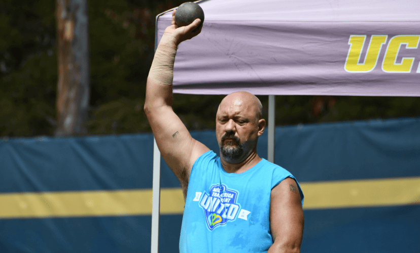 Will Klein participates in the shotput competition at the Transplant Games of America, holding the shot high in the air with his right hand
