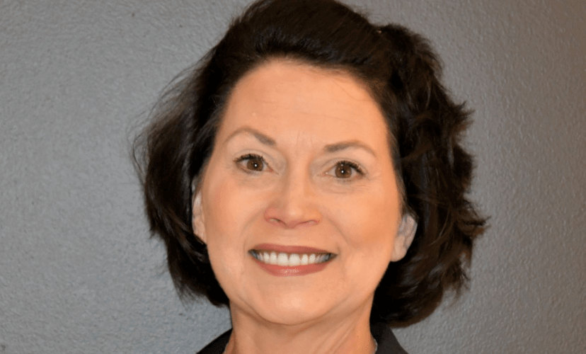 A woman with dark hair smiles at the camera