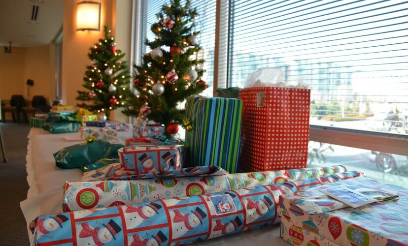 Christmas presents and two small Christmas trees sit on top of a long table