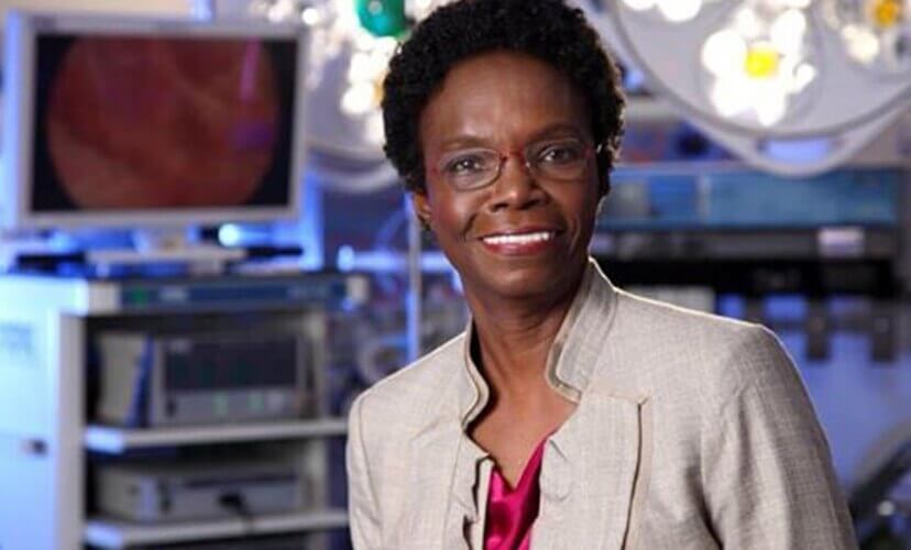 Dr. Velma Scantlebury-White, wearing business attire and pictured with an operating room in the background