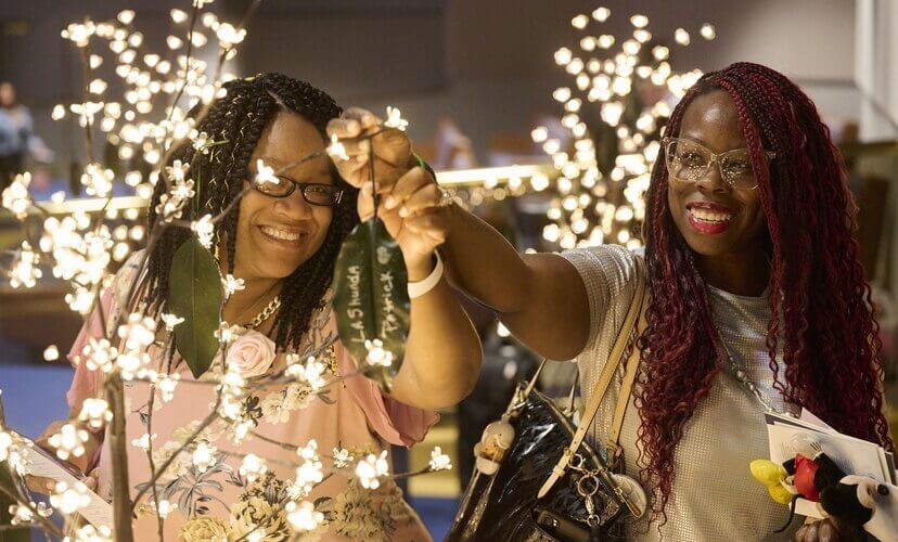 Donor family members hang leaves with the name of their loved ones at a Candlelight memorial. They are hanging leaves on small trees covered with twinkle lights.