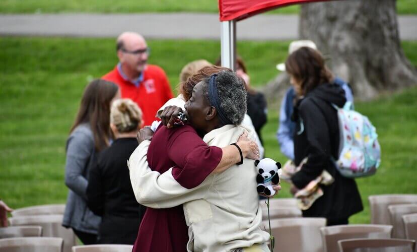 Two women hug at a candlelight memorial for organ and tissue donor heroes