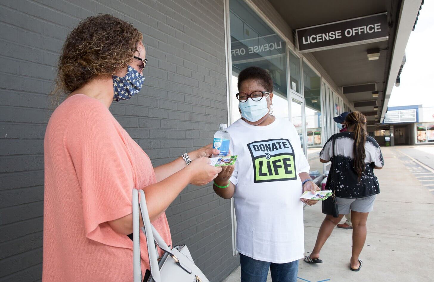 A Mid-America Transplant volunteer hands out water and information about organ and tissue donation at the Florissant DMV.