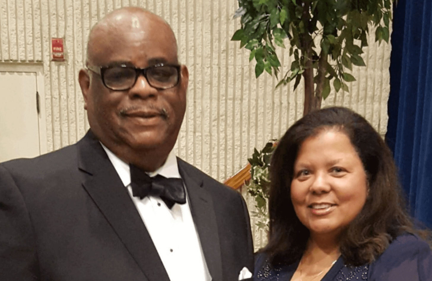 A man and woman pose together in formalwear.