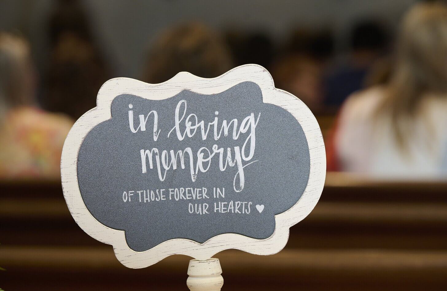 A dark sign with white text and a white border reads " In loving memory of those forever in our hearts"