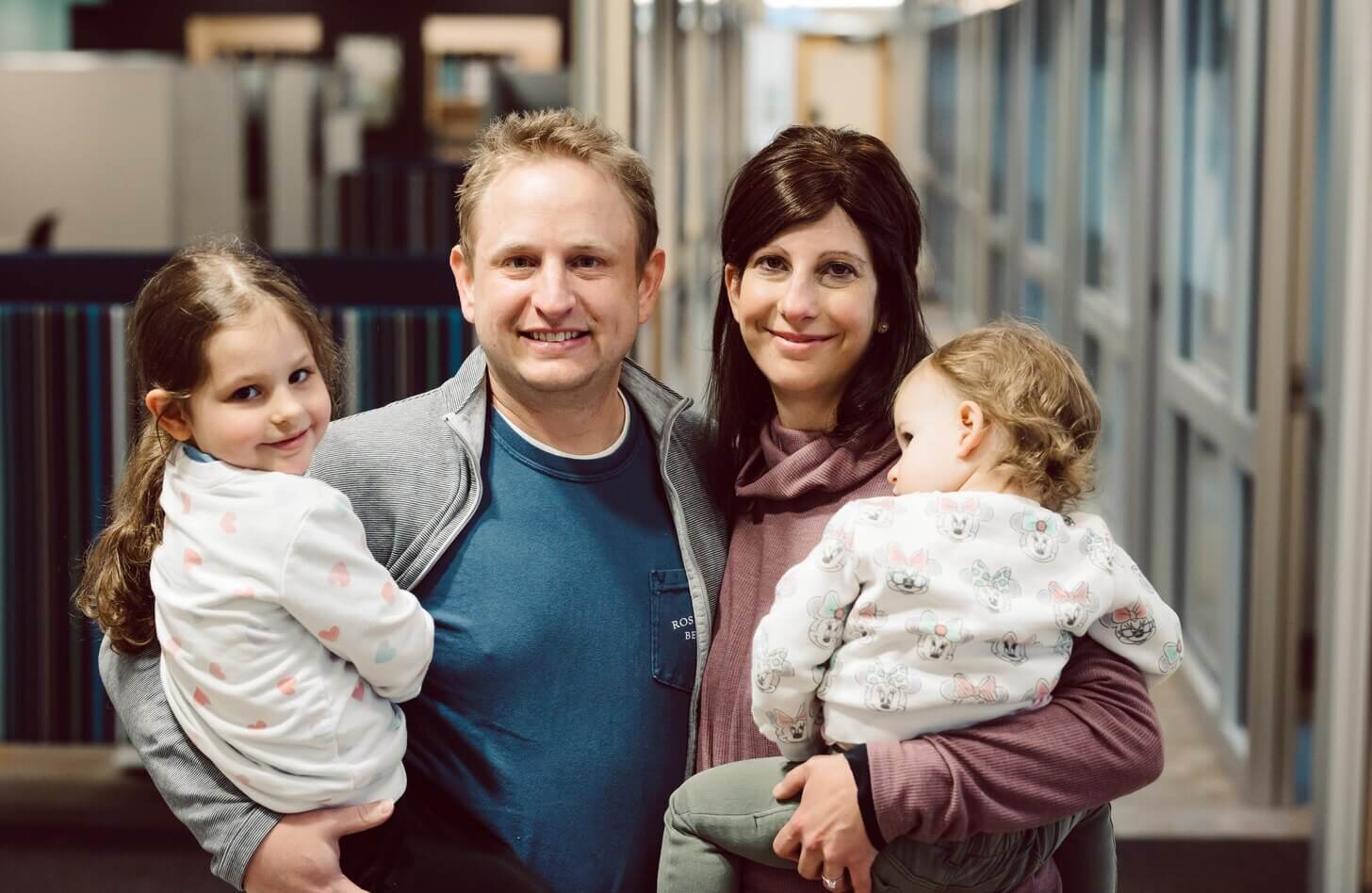 A family stands together. Parents hold two children, one of which has had a liver transplant.