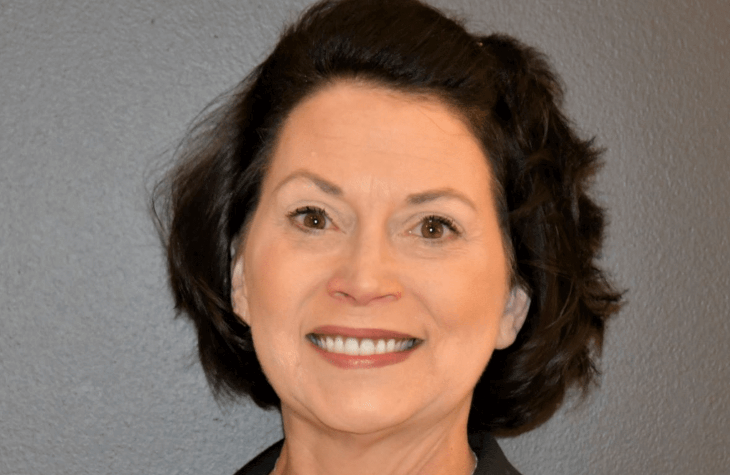 A woman with dark hair smiles at the camera