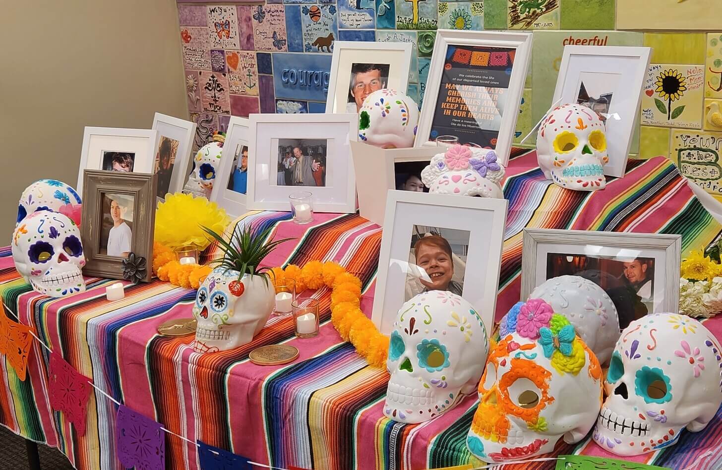An altar is decorated for Dia de los Muertos with sugar skulls and photos of loved ones.