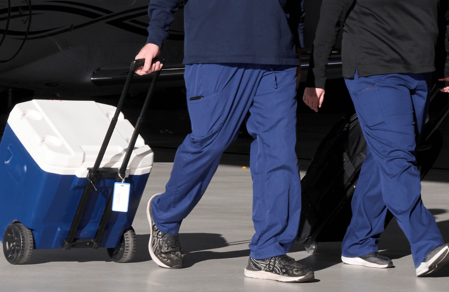 Two nurses in scrub pants transport an organ