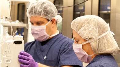 Man and woman in scrubts looking at a medical machine