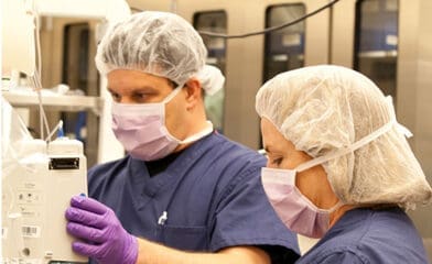 Man and woman in scrubts looking at a medical machine