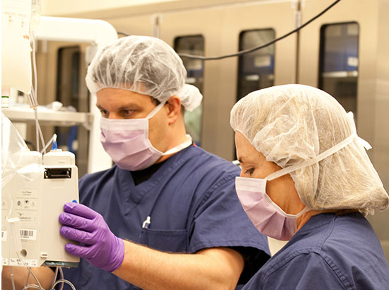 Man and woman in scrubts looking at a medical machine