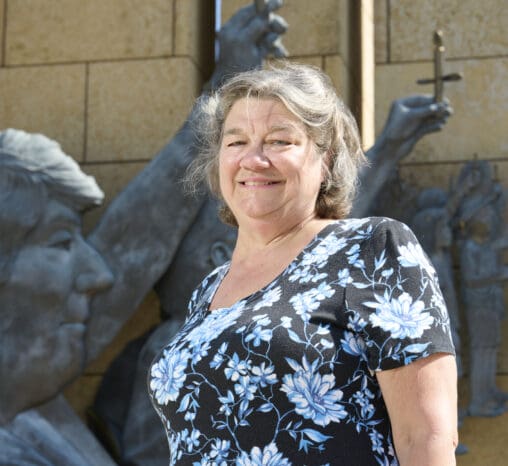 June, a donor mom, stands in front of the donor memorial on a bright and sunny day
