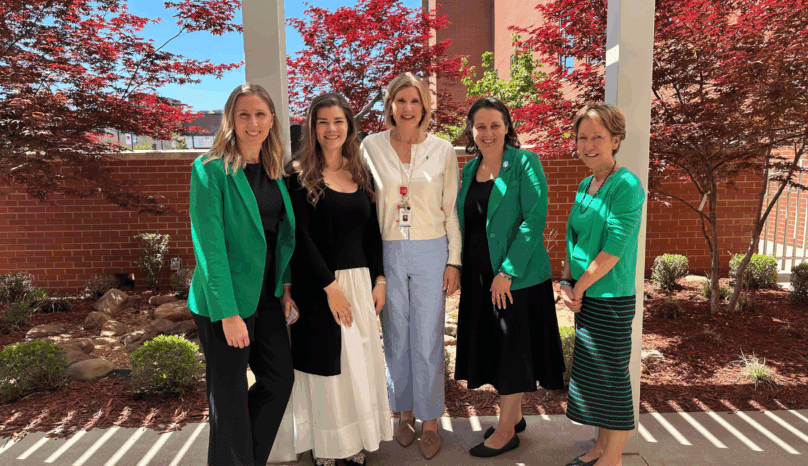 Five employees stand in front of a donor memorial in Jonesboro, Arkansas